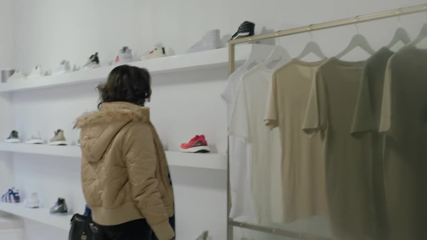 Woman looks at a rack of clothing in a store