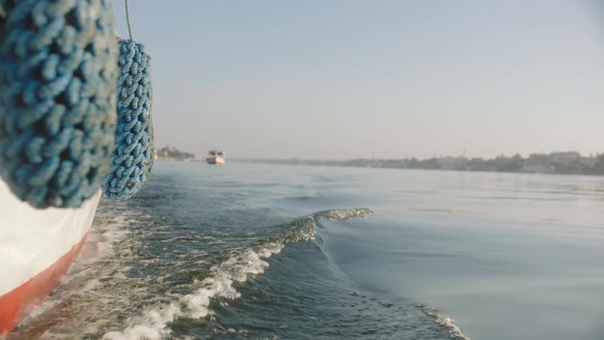 Slow motion close-up of the wake from a boat cruising along a wide river on a hazy day