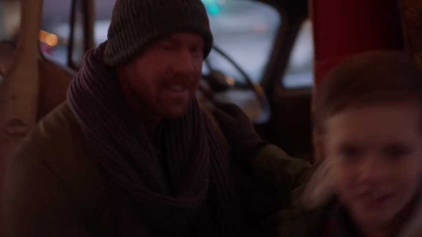 A man helps a boy out of a truck