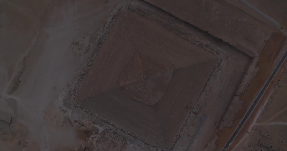 A breathtaking aerial top-down shot slowly pulls away from the apex of a famous Giza pyramid in the Egyptian desert