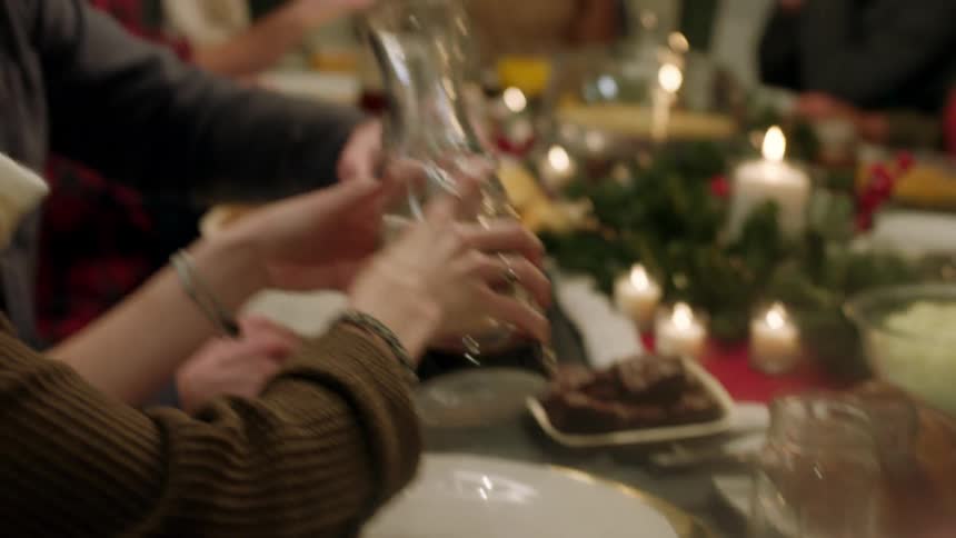 Group of people at christmas dinner table talking and pouring a drink