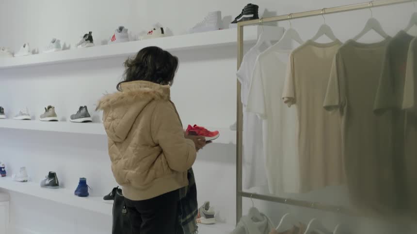 A woman looks at a shoe in a clothing store