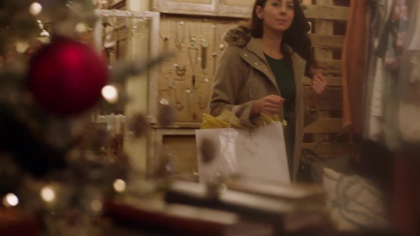 A woman carries a package as she walks through a shop