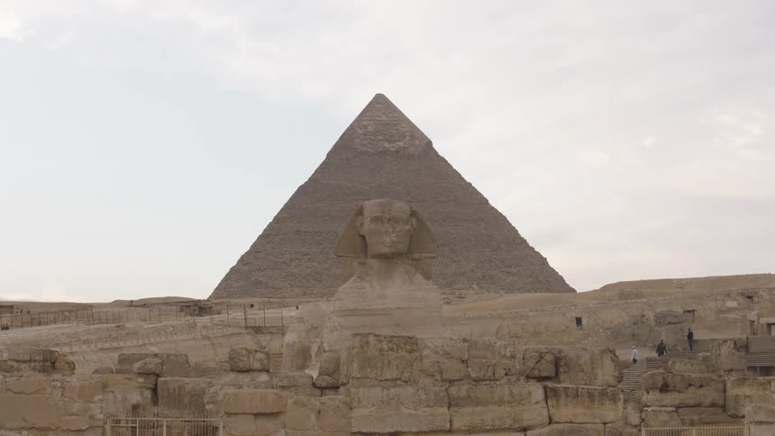 Iconic view of the Great Sphinx of Giza standing before the Great Pyramid on a hazy day