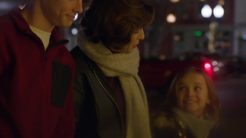 Woman and three children stand in the middle of the city at night