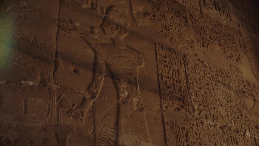 A close-up slow pan reveals ancient Egyptian hieroglyphics and relief carvings on a temple wall