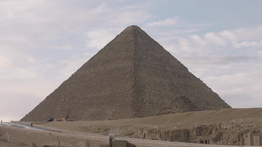 A slow camera tilt down from the sky reveals the magnificent Great Pyramid of Giza standing in the desert