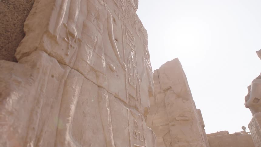 A slow, detailed pan down an ancient Egyptian hieroglyphic carving on a stone wall at a temple