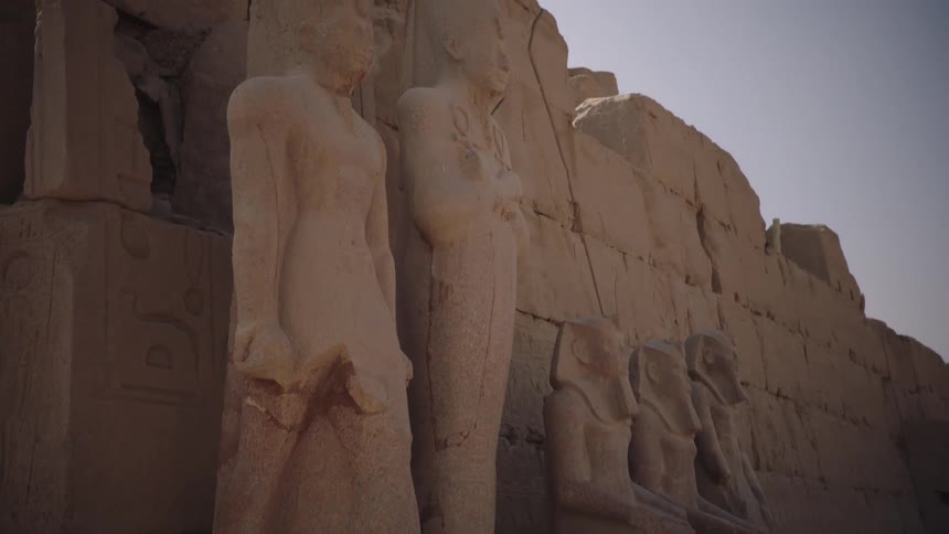 A slow tilt up of the majestic ancient statues standing guard at the Karnak Temple in Egypt