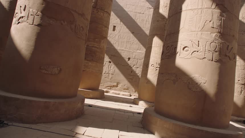 A slow pull-back shot reveals the immense scale of the ancient hieroglyph-covered columns of an Egyptian temple