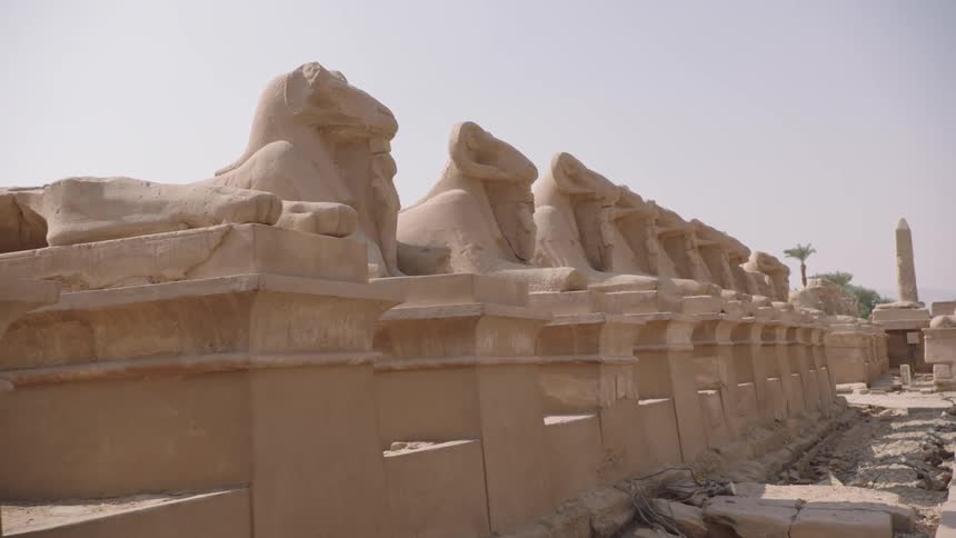 A slow tracking shot moves along the historic Avenue of Sphinxes at the Karnak Temple complex in Egypt