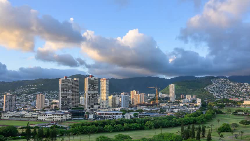 A scenic day to night timelapse of the Honolulu city skyline in Hawaii with dramatic clouds moving over the mountains