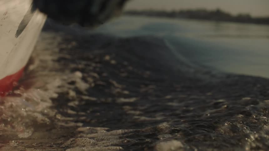 A mesmerizing slow-motion close-up of a boat's hull cutting through the calm water and creating a gentle wake