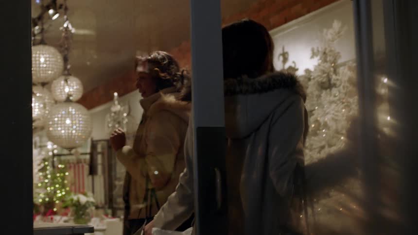 Two women entering a store to shop on a holiday time evening