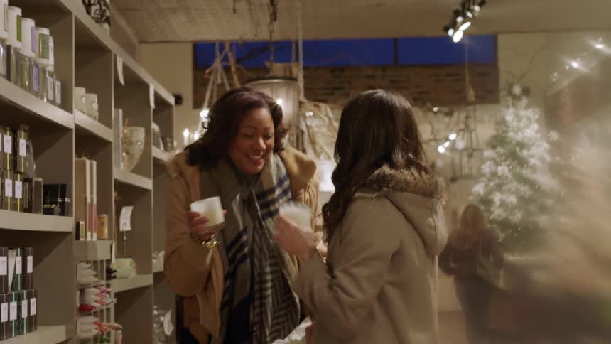 Two women smell candles in a store