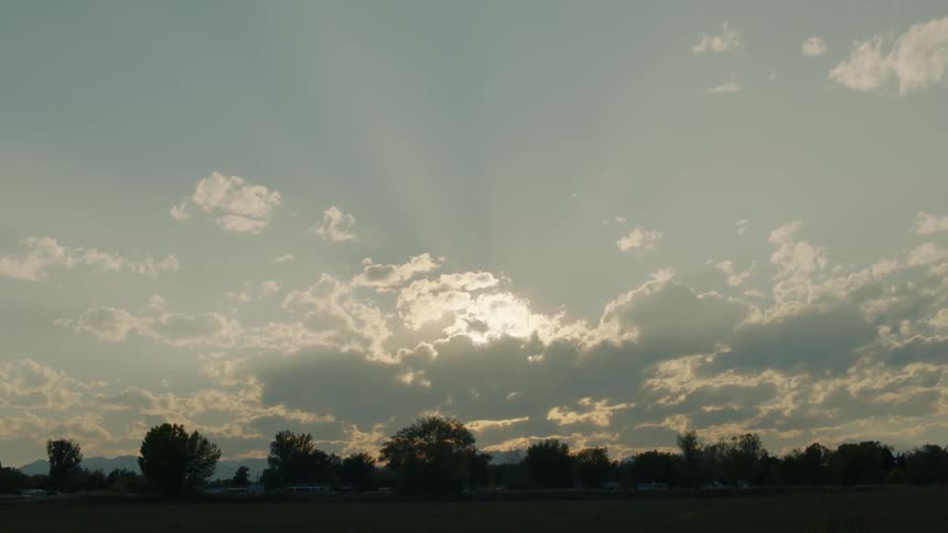 Clouds float over trees in a rural area