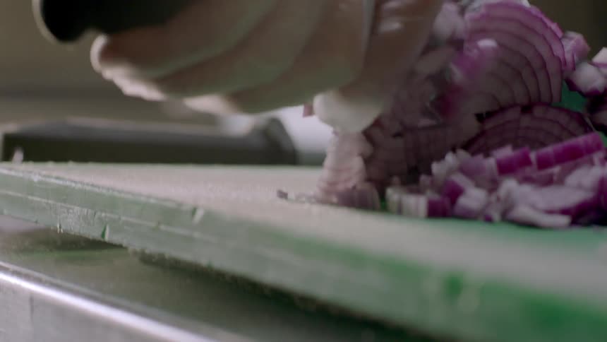 A person dices an onion into small pieces