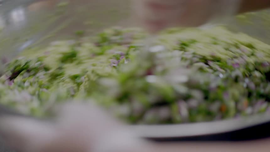 A person uses a spatula to stir ingredients together in a bowl