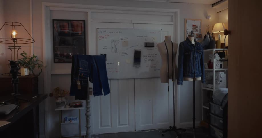 A fashion designer's creative studio with denim clothing, mannequins, and a whiteboard of design plans