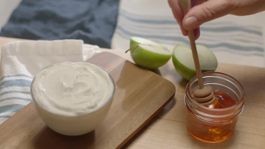 The table has apples, honey, and cream