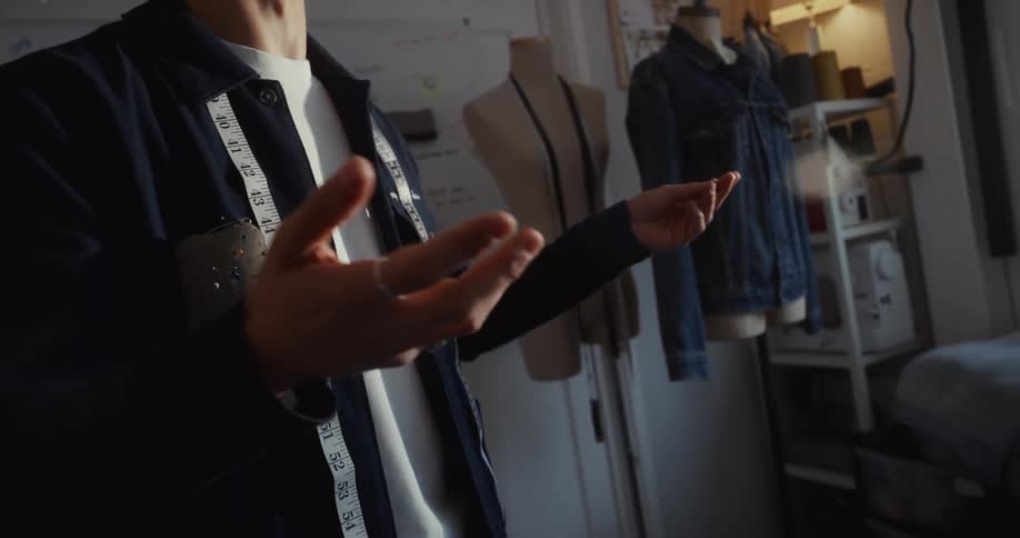 Close-up slow motion shot of a passionate male tailor talking and gesturing in his sunlit design studio