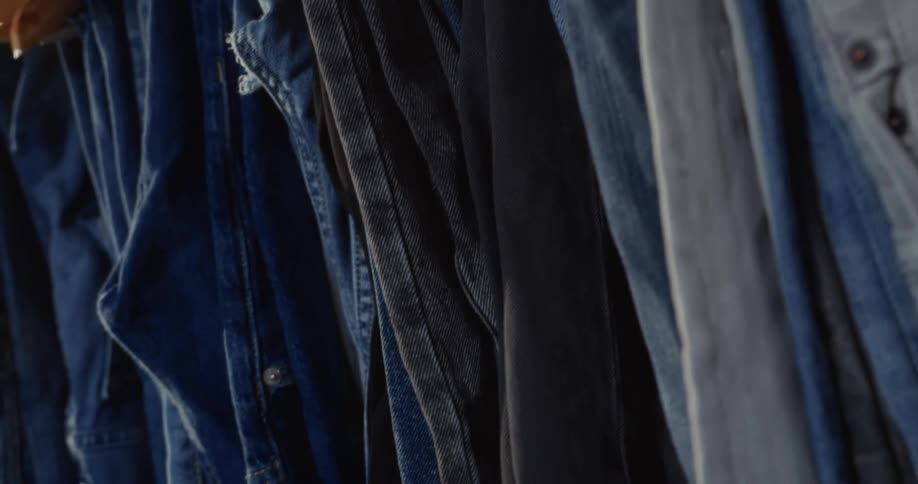 A slow pan reveals a collection of various denim shirts and jackets hanging on a clothing rack