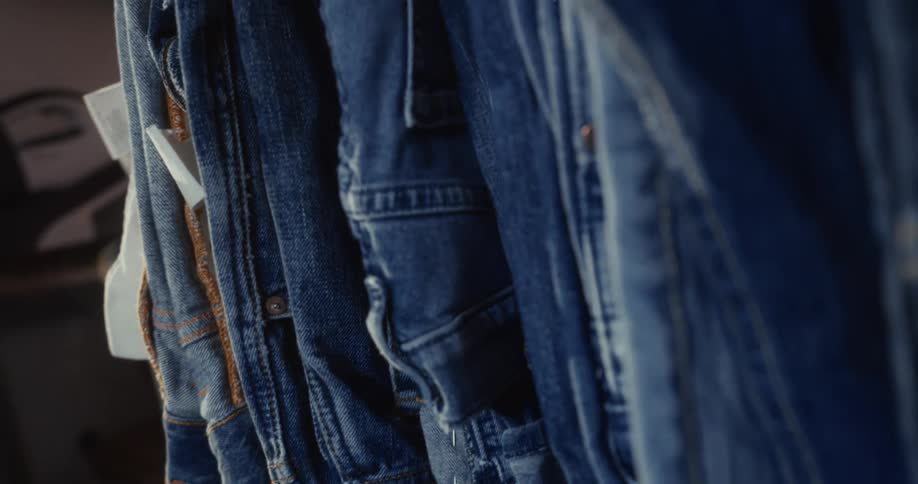 A stylish close-up pan reveals a collection of classic blue denim jackets hanging on a clothing rack