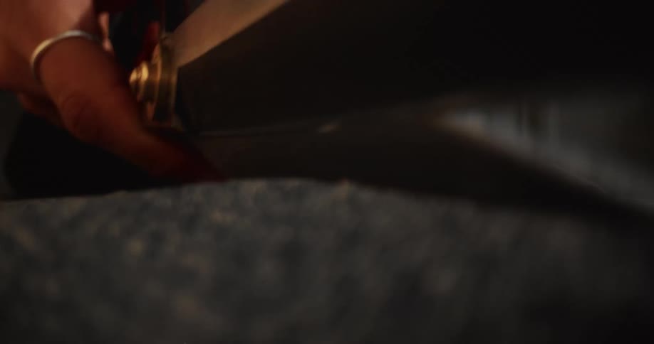 An extreme close-up shot shows a pair of sharp scissors slowly cutting through blue denim fabric