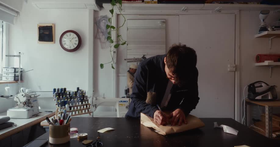 A young artisan in his workshop carefully seals and addresses a package for a customer