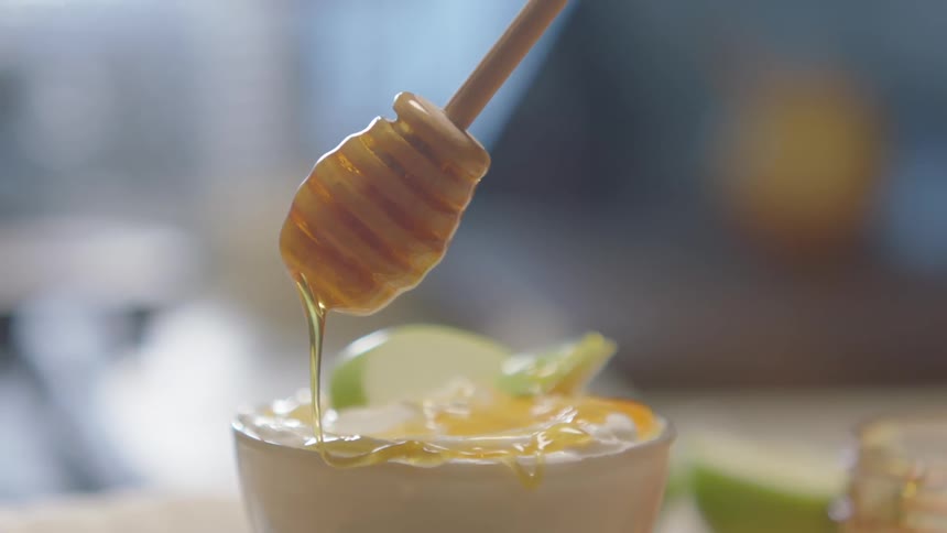 Honey is being poured into a mug