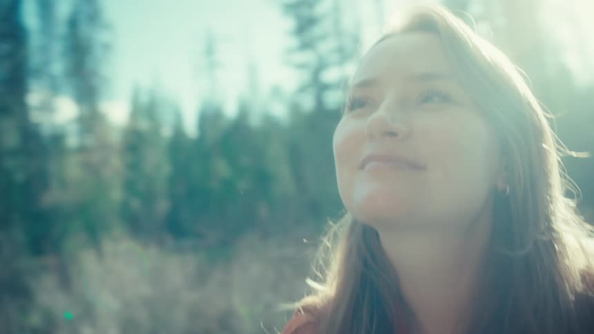 Dreamy slow-motion shot of a beautiful woman enjoying a tranquil moment in a sun-drenched forest