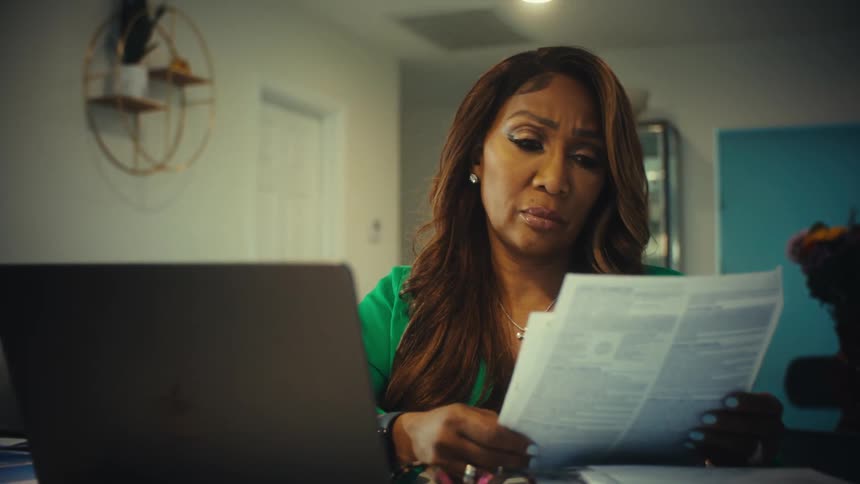 A stressed and frustrated woman overwhelmed by bills throws papers in anger while working on her finances at home
