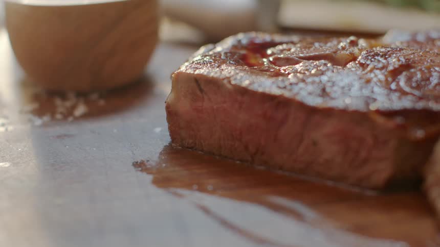 A steak is being cut on a board