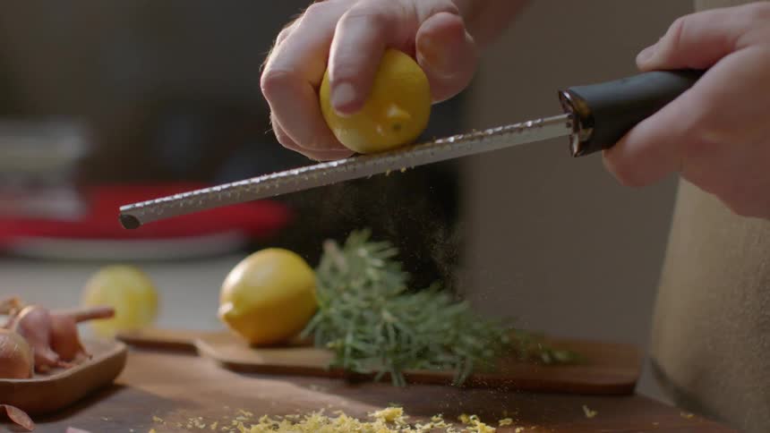 A person uses a shaver to mince lemon skin