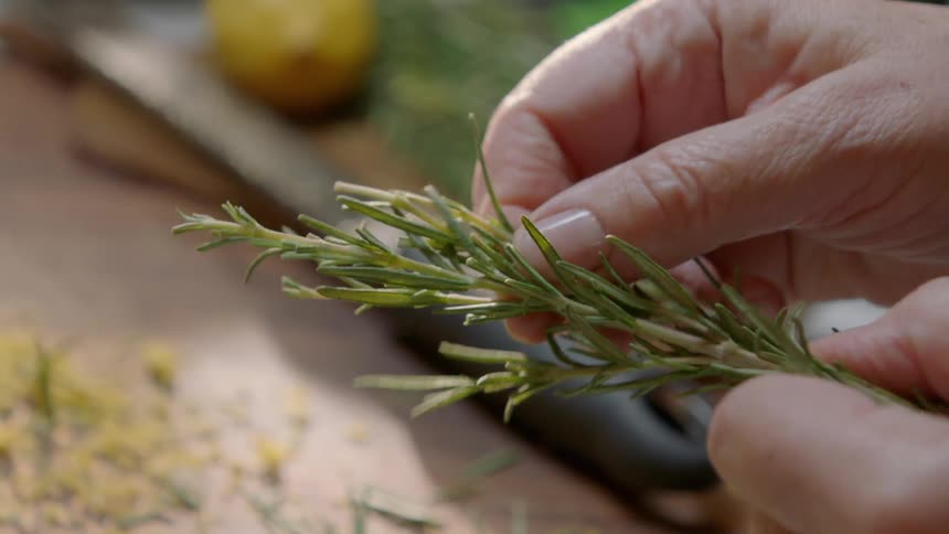 A person pulls apart parsley on a board