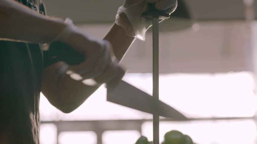 A man is sharpening his knife in a kitchen