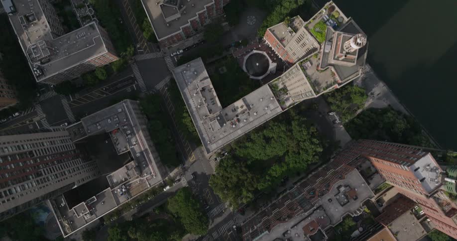 An overhead aerial shot slowly pans over a city neighborhood, showing buildings, trees, and streets