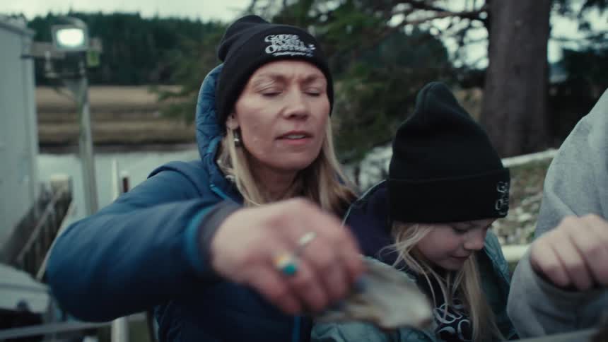 A mother teaches her young daughter about oysters as they sort through the fresh catch at their family farm