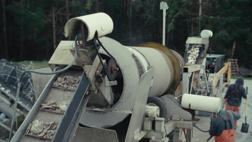 Freshly harvested oysters are sorted and processed by a large trommel machine on a commercial oyster farm