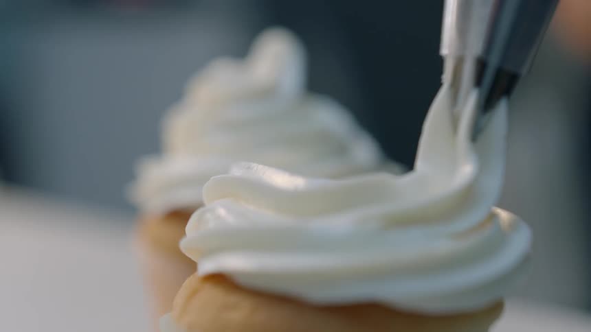 Frosting is piped onto a cupcake