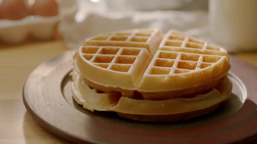 Homemade waffles sit on a wood plate