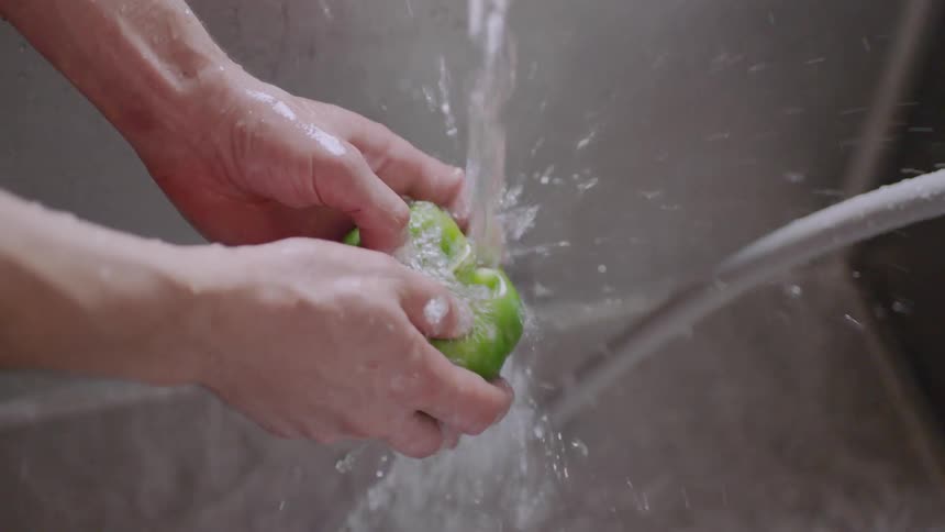 A person is washing a pepper