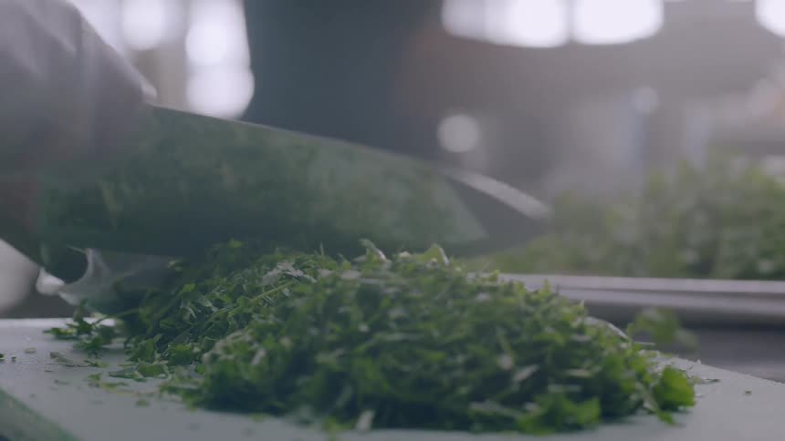 Person chopping up parsley on cutting board in kitchen