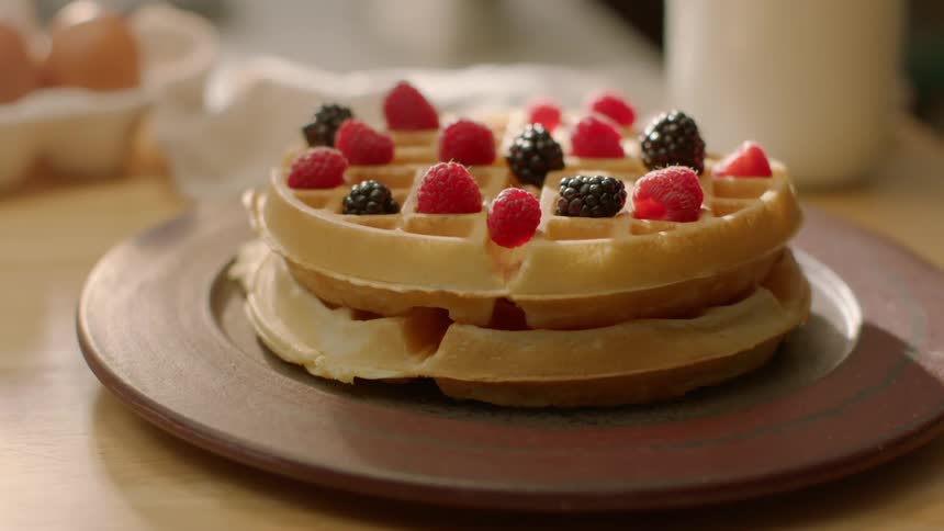 Berries have been placed on two waffles sitting on a plate