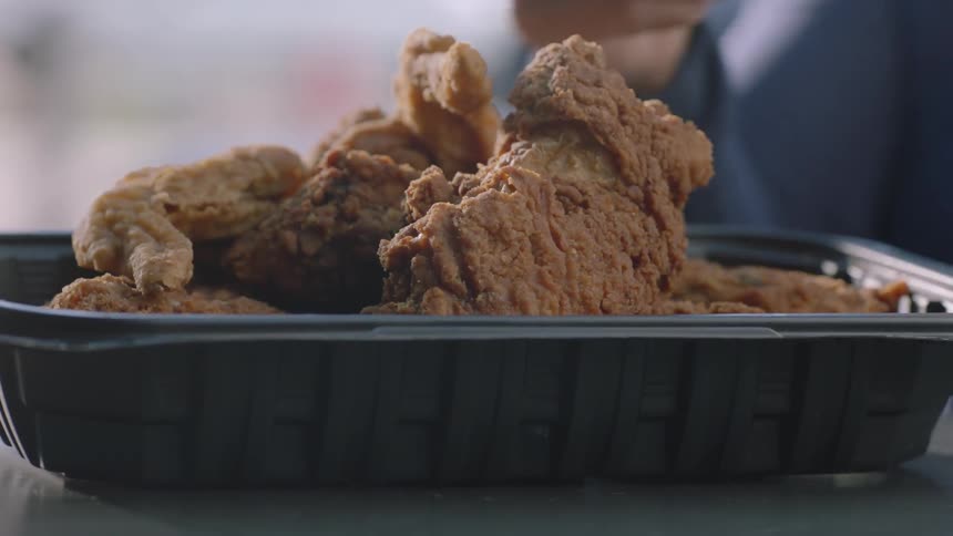 Someone grabs a piece of chicken from the platter