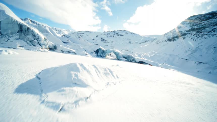 A thrilling FPV drone flight over a vast snowy glacier, diving through a natural ice arch on a bright sunny day