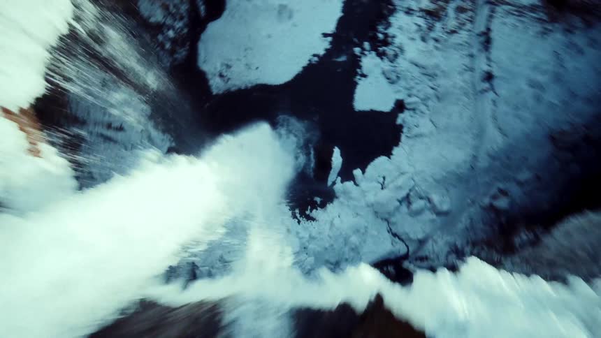 A thrilling FPV drone dive down a majestic, snow-covered waterfall into a narrow icy canyon