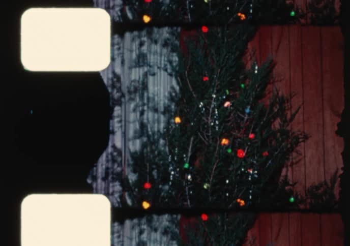 A vintage 16mm film captures two women decorating a Christmas tree in their retro-style home