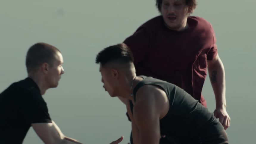 A slow motion reveal of a diverse group of young men playing an intense game of basketball outdoors