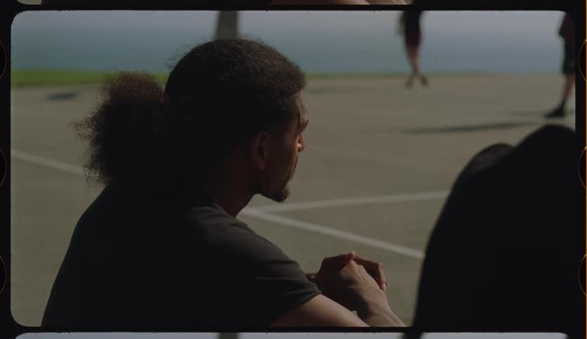 A young man on a basketball court sideline goes through a range of emotions from laughter to sadness in slow motion
